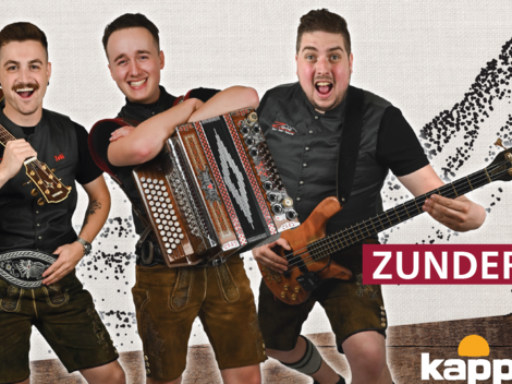 Three cheerful musicians in traditional attire stand together. They hold various instruments and smile at the camera.