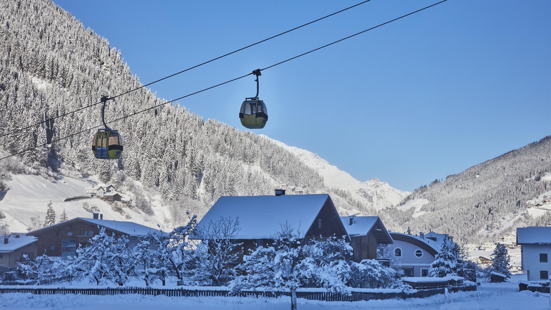 Ein Skifahrer fährt die schneebedeckte Piste hinunter. Im Hintergrund sind majestätische Berge zu sehen.