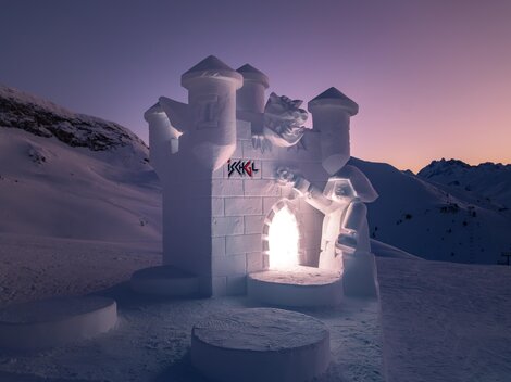 An impressive snow castle masterpiece in a snowy landscape. The castle glows gently in the twilight.