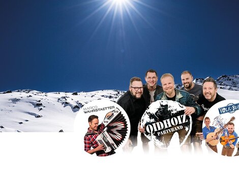 A group of musicians stands in front of a snowy mountain landscape. In the background, the sun shines in the clear sky.