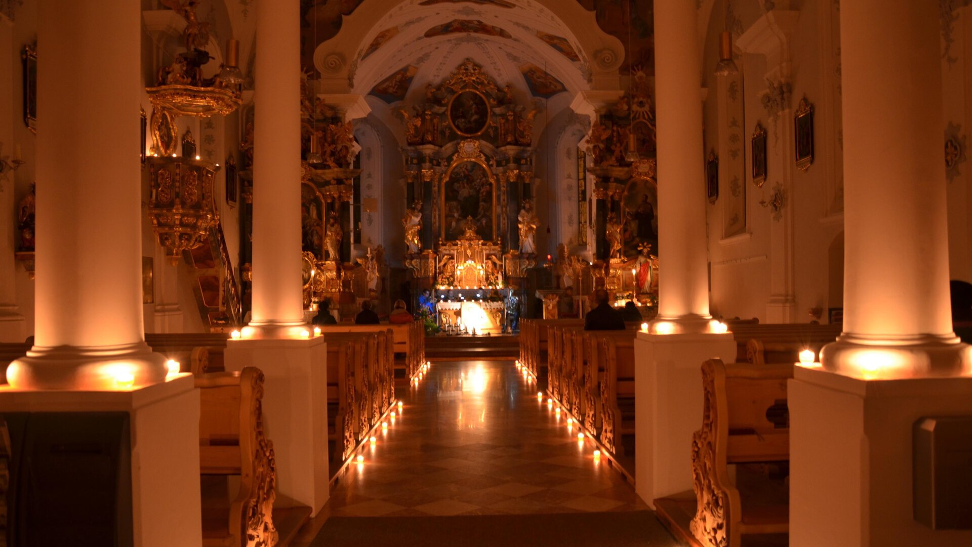Eine wunderschöne Kirche mit sanfter Beleuchtung und einer beeindruckenden Altaranordnung. Der Raum strahlt eine ruhige und besinnliche Atmosphäre aus.