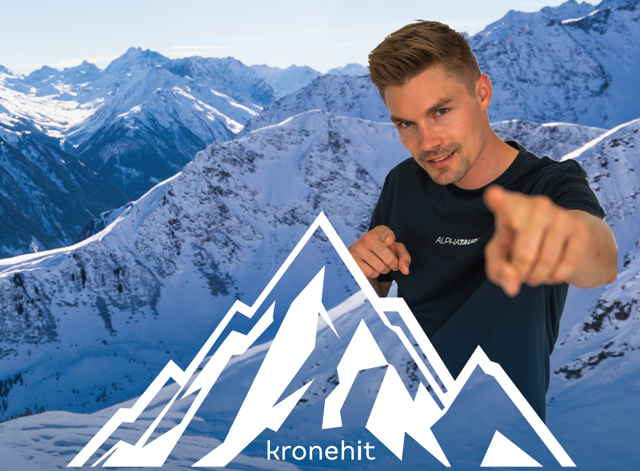 A man stands in front of snow-covered mountains and points forward with his finger. In the foreground, the logo of Kronehit is visible.