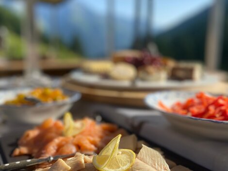 An attractively arranged selection of fish platters, garnished with lemon. In the background, other dishes and a beautiful landscape can be seen.