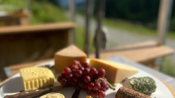 A plate with various types of cheese, grapes, and nuts. The presentation takes place in a beautiful setting with a view.