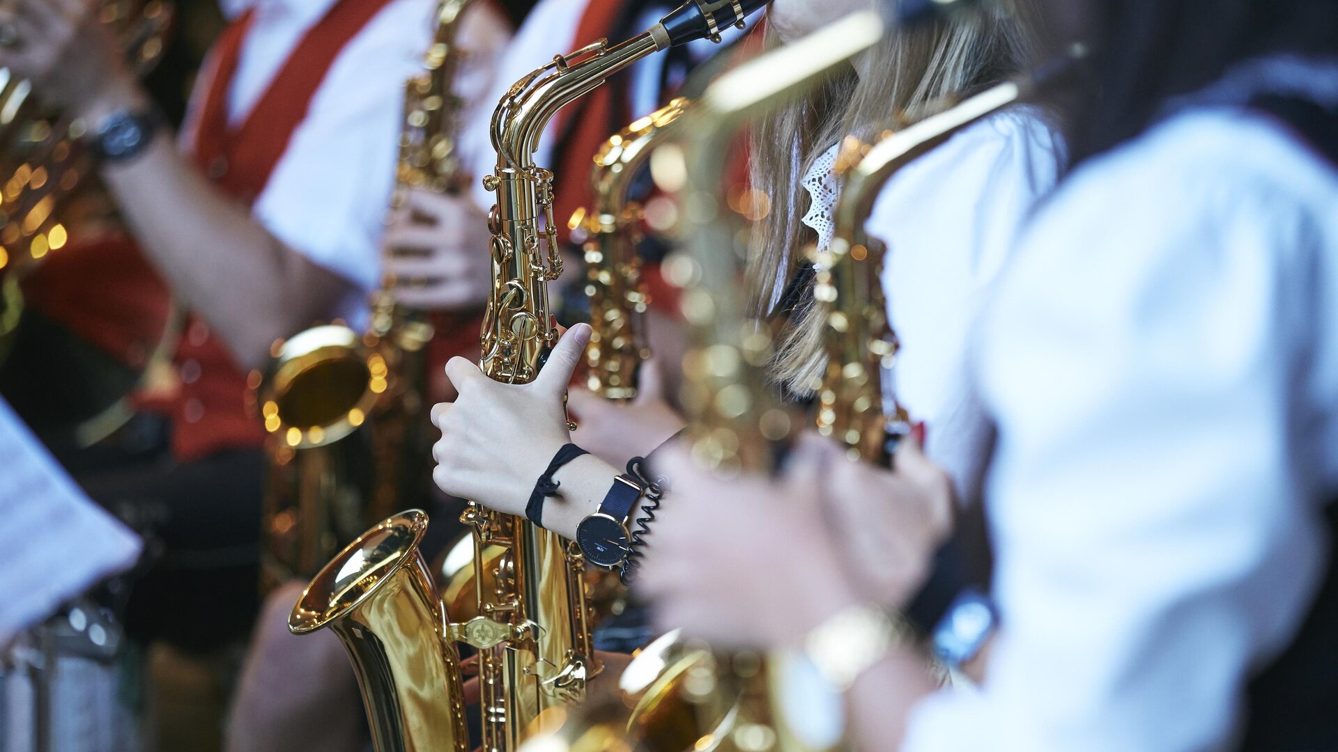 Eine Gruppe von Musikern spielt Saxophon. Sie tragen traditionelle Kleidung und konzentrieren sich auf ihre Instrumente.