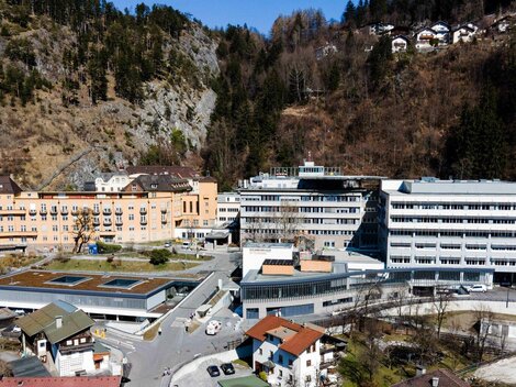 Eine moderne Gebäudekomplex in einer bergigen Umgebung. Mehrere Gebäude sind sichtbar, umgeben von Bäumen und Hügeln.