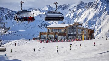 A snow-covered mountain landscape with the Flimjochbahn B2 in the foreground. Skiers and snowboarders are enjoying the day on the slopes.