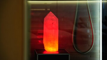 A glowing salt stone stands on a pedestal, adding a warm atmosphere to the room. In the background, a shower fixture is visible.