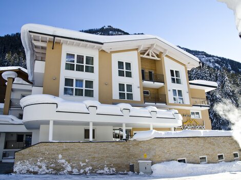 A modern building in a snow-covered landscape. The facade is bright and inviting, surrounded by mountains.
