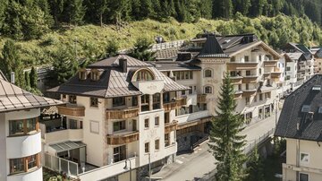 A picturesque alpine landscape with modern buildings. In the background, green hills and forests can be seen.