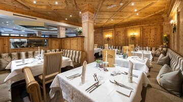 A cozy restaurant with wooden paneling and elegant tables. The atmosphere is inviting and warm.