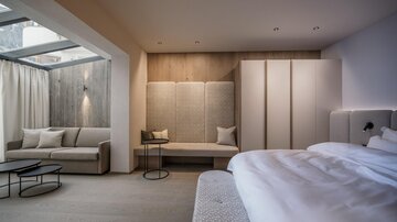A modern room with a bright bedroom and a cozy seating area.  
Large windows ensure plenty of daylight and an inviting atmosphere.