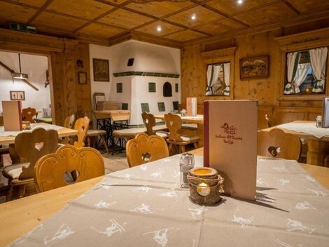 A cozy restaurant with wooden paneling and rustic tables. The tables are neatly set, and there is an inviting atmosphere.