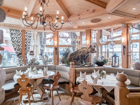 A cozy restaurant with wooden decor and a bear figure in the background. The tables are nicely set, creating an inviting atmosphere.