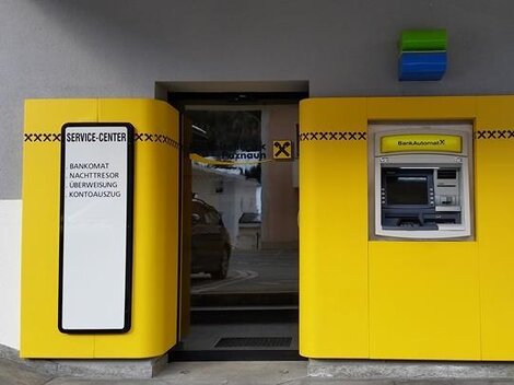 Ein Service-Center mit einem Geldautomaten und einem Eingang. Die Wände sind in leuchtendem Gelb gestaltet.
