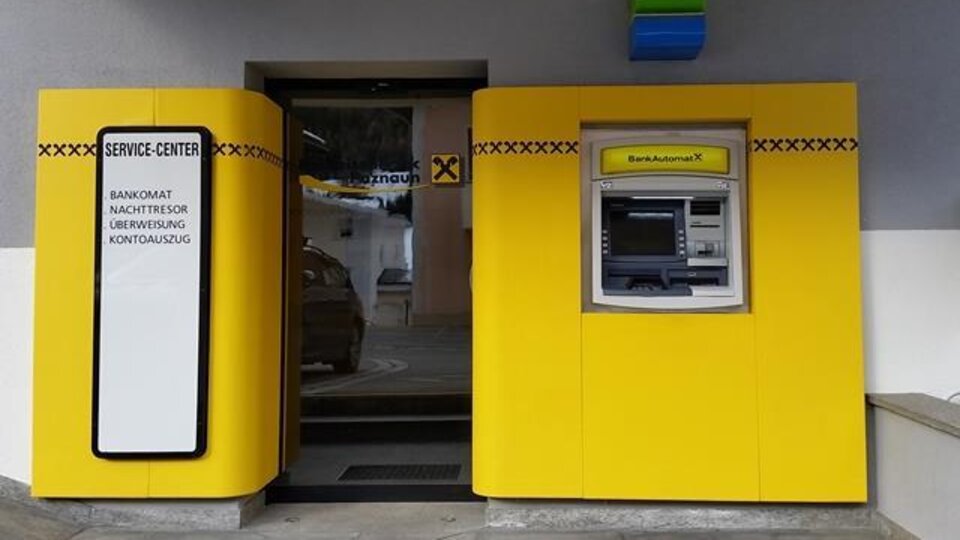 Ein Service-Center mit einem Geldautomaten und einem Eingang. Die Wände sind in leuchtendem Gelb gestaltet.