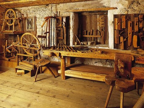 A traditional workshop with various woodworking tools. The wooden surfaces and furniture create a rustic atmosphere.