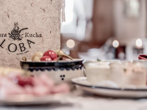 A decorative restaurant menu named "Loba" is prominently displayed in the foreground. In the background, there are various small dishes and snacks.