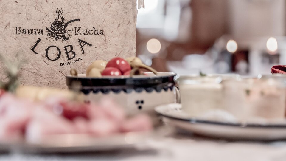 A decorative restaurant menu named "Loba" is prominently displayed in the foreground. In the background, there are various small dishes and snacks.