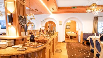 An inviting restaurant with warm wooden elements and cozy tables. The counter is decorated with delicious sweets.