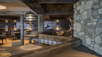 A cozy restaurant with wooden elements and stone walls. The lighting creates a warm and inviting atmosphere.