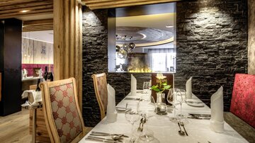 An elegant restaurant with a beautifully set table and stylish interior. In the background, there is a modern fireplace and decorative elements.