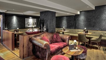 A cozy interior with a large leather sofa and wooden details. The atmosphere is warm and inviting, ideal for relaxed gatherings.