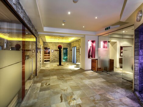 An elegant entrance area with modern materials and gentle lighting. The walls are made of natural stone, and there are areas with various facilities.