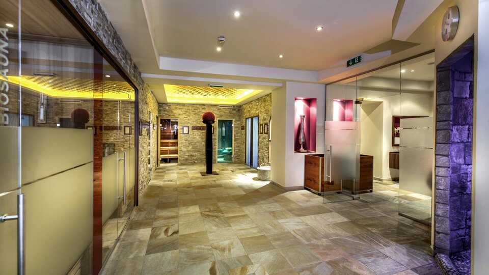 An elegant entrance area with modern materials and gentle lighting. The walls are made of natural stone, and there are areas with various facilities.