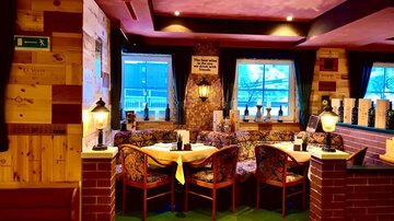 Cozy restaurant with wooden walls and comfortable seating. Large windows provide plenty of light and an inviting view outside.