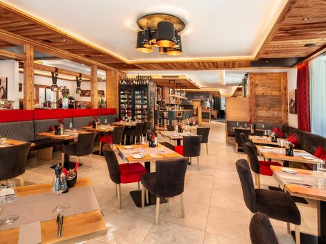 A modern restaurant with wooden paneling and cozy seating. The tables are neatly set, and there is an inviting atmosphere.