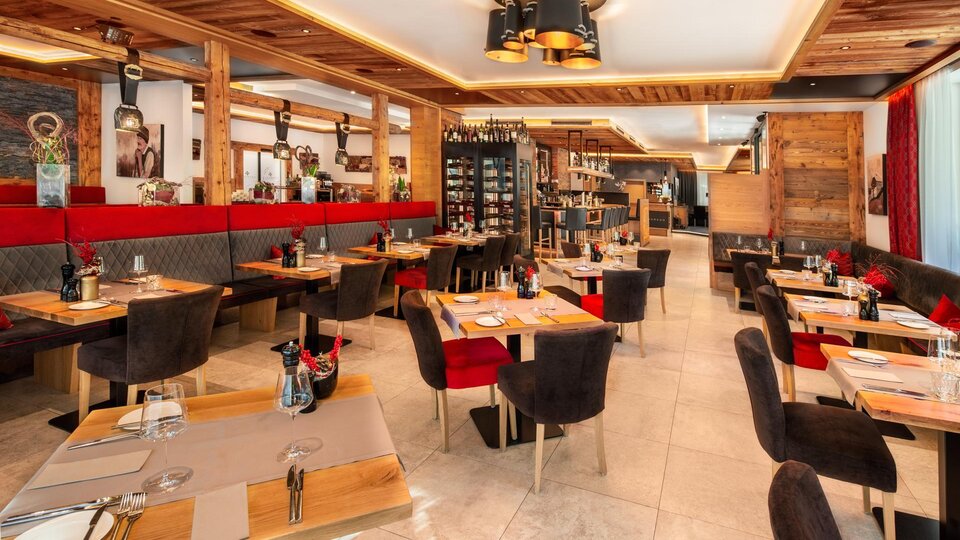A modern restaurant with wooden paneling and cozy seating. The tables are neatly set, and there is an inviting atmosphere.