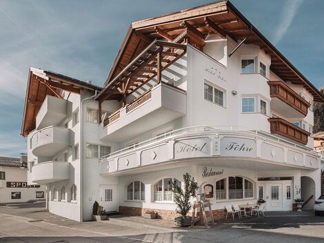 A modern hotel building with a distinctive roof and an inviting facade. It is located in a picturesque mountain landscape.