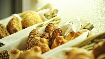 A selection of fresh pastries in baskets. The breads are golden brown and invite you to indulge.