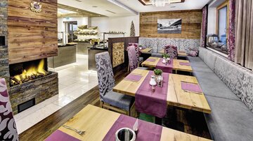 A cozy restaurant with wooden decor and elegant tables. The warm atmosphere is emphasized by a fireplace and stylish furnishings.
