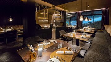 An elegant restaurant with modern tables and chairs. The atmosphere is cozy and stylish, with a panoramic view.