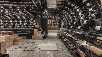 An elegant wine cellar with many wine bottles on shelves. The room has a modern atmosphere with stylish design and lighting.
