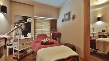 A stylish wellness room with comfortable treatment beds and cosmetic utensils. The walls are in soft colors, creating a relaxing atmosphere.
