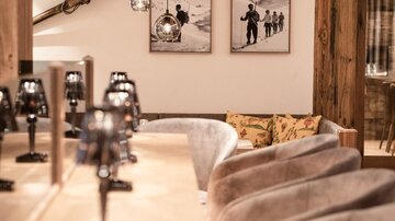 A cozy, modern interior with a counter and elegant chairs. Pictures of people in the mountains hang on the walls.