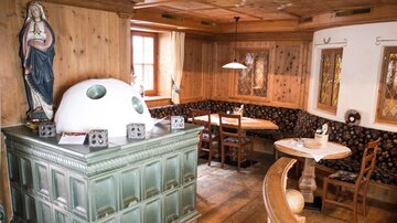 A cozy restaurant with wood paneling and traditional furniture. A statue in the corner gives the room a rustic atmosphere.
