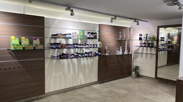 A modernly designed room with shelves full of health products. Various bottles and packages can be seen on wooden shelves and a mirror on the wall.