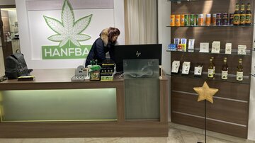 A modern shop with a reception desk and hemp products. In the background, various hemp products and a logo with a leaf can be seen.