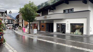 A quiet street in a village with modern shops. The sky is cloudy and the street is wet from the rain.
