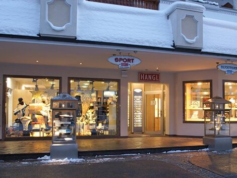 A sports store with a snow-covered facade. In the shop window, various sports items and clothing are visible.