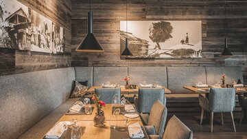 Ein gemütliches Restaurant mit Holzwänden und stilvollen Möbeln. Auf den Tischen sind Besteck und Blumendekorationen arrangiert.
