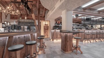 A modern restaurant with wooden decor and stylish bar stools. The pleasant lighting creates an inviting atmosphere.