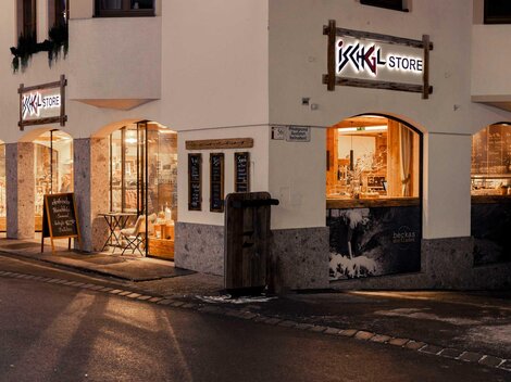 A cozy shop in a city with inviting lighting. The windows display various products and a popular shopping destination.