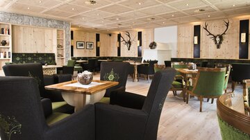 A modern restaurant with bright wooden decor. The furnishings include elegant chairs and table groups in a cozy atmosphere.