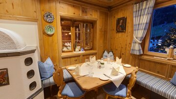 A cozy seating area in a wood interior with a round table. Decorative plates hang on the walls, and a window lets light in.