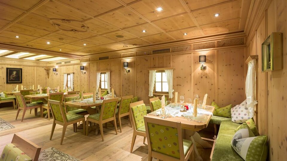 A cozy room with wooden walls and elegant furnishings. Several tables and chairs are ready for guests.
